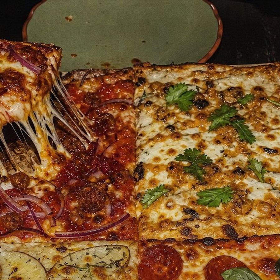 A square-cut Squared Seasons pizza on a board, different flavours in each quarter